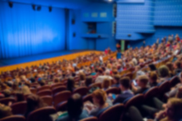 Theatre stage. Blue curtain. Defocused image, bokeh effect. People in the auditorium of the theater or concert hall.