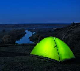 Wall Mural - lighted from the inside green tents on hill above river