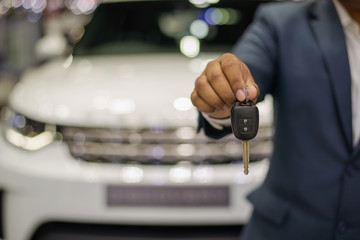 male adult businessman in a suit giving a car keys, salesman handing over your new car keys, dealership and sales concept