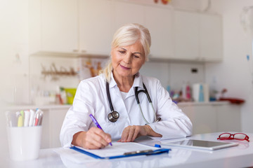 Sticker - Senior female doctor writing a prescription in her office