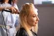 beautiful adult blonde client sits in a chair while a hairdresser master in the salon does her hair with a corrugation and a Perm