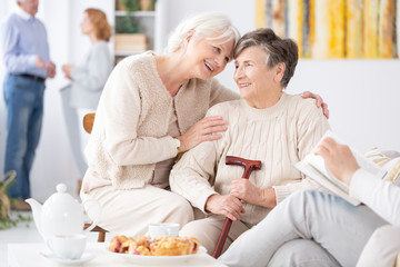 Two smiling senior best friends spending time together at school reunion