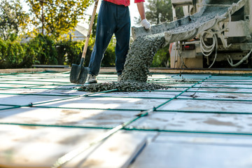 Mixer track pouring wet cement to the civil building foundation. Construction workers in the process of forming house concrete slab at the construction site.