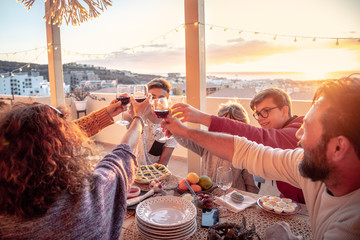 Group of friends celebrating toasting with drinks the new year. Male and female friends make toast Aas they celebrate at party. Group of people with teen laughing out loud outdoor with glasses in hand