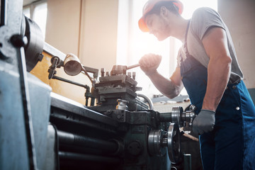 Portrait of a young worker in a hard hat at a large metalworking plant. The engineer serves the machines and manufactures parts for gas equipment