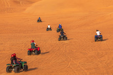 Tourists Having Fun Riding Quad Bikes In Dunes Of Dubai Adventure Tour