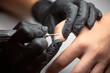 © anatoliy_gleb - Finger nail treatment, fashion, manicure making process in beauty salon Electric nail file drill in action, close up of beautician hands in black gloves working on client fingernails.