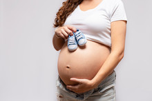 Close-up Of Pregnant Woman With Baby Shoes On Her Belly