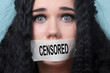 portrait of young woman with mouth and lips sealed in adhesive tape restrained and abused censored and banned to speak, concept of hostage