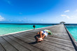 Junger Mann mit grünem Hemd liegt auf einem Steg auf den Malediven