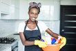 © F8  \ Suport Ukraine - Smiling young african woman holding basket with cleaning equipment at hause