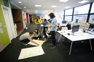 Wall Mural - Startup business people in modern office. Group of young business people are working together with laptop. Freelancers sitting on the floor. tech startup, tech team.