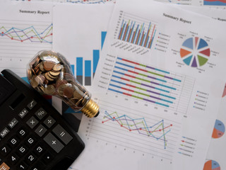 Wall Mural - top view light bulb with coin and calculator on business graph. concept of cost reduction and reduce
