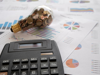 Wall Mural - light bulb with coin and calculator on business graph. concept of cost reduction and reduce energy. 