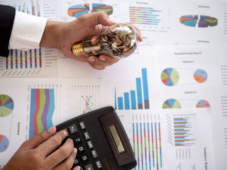 Wall Mural - hands of businessman holding a light bulb and use calculator calculate the costs need to be reduced.