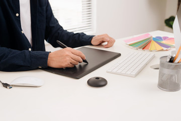 Fototapete - Photographer sitting at desk retouching new photos in his studio