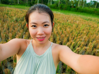 young happy and attractive Asian Korean woman taking selfie self portrait with mobile phone at tropical island posing cheerful and relaxed exploring rice field enjoying holidays