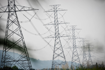 Group silhouette of transmission towers (power tower, electricity pylon, steel lattice tower) at cloudy sky in Thailand. Texture high voltage pillar, overhead power line, industrial background. 