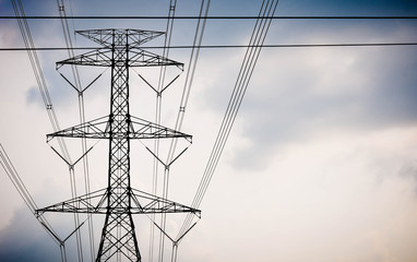 Group silhouette of transmission towers (power tower, electricity pylon, steel lattice tower) at cloudy sky in Thailand. Texture high voltage pillar, overhead power line, industrial background. 