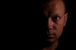 © flexelf - Portrait of a serious man face in darkness.