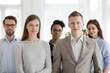 Portrait of successful millennial multiracial people stand looking at camera, team of young employees or workers smiling posing for picture together, diverse company professionals or staff in office