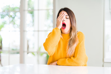 Poster - Young beautiful woman wearing winter sweater at home Yawning tired covering half face, eye and mouth with hand. Face hurts in pain.