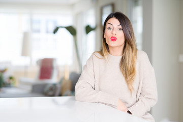 Sticker - Young beautiful woman wearing winter sweater at home puffing cheeks with funny face. Mouth inflated with air, crazy expression.