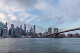 Fototapeta  - View of Manhattan with Brooklyn Bridge at sunset from the side of the pier.