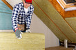 © artursfoto - Man installing thermal roof insulation layer - using mineral wool panels. Attic renovation and insulation concept