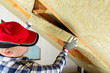 © artursfoto - Man installing thermal roof insulation layer - using mineral wool panels. Attic renovation and insulation concept