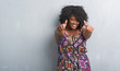 © Krakenimages.com - Young african american woman over grey grunge wall wearing colorful dress approving doing positive gesture with hand, thumbs up smiling and happy for success. Looking at the camera, winner gesture.