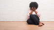 © Krakenimages.com - Young african american woman sitting on the floor at home with sad expression covering face with hands while crying. Depression concept.