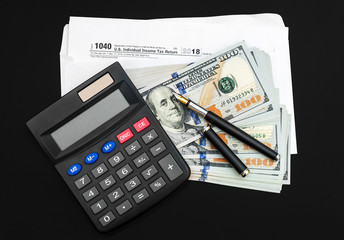 Calculator with money and envelope with tax form on black background.