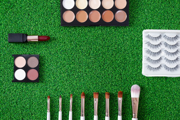 Top view of women's cosmetic on green background.