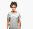 © Krakenimages.com - Young afro american woman wearing glasses over isolated background skeptic and nervous, frowning upset because of problem. Negative person.