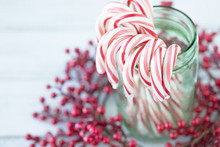 Christmas Photograph Of Candy Canes In A Green Mason Jar With Red Berries On White