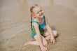 маленькая девочка со светлыми волосами сидит на берегу моря в воде little girl with blond hair sitting on the beach in the water