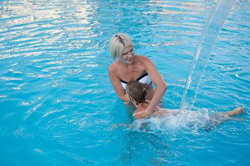 Wall Mural - Happy mother and daughter playing in swimming pool