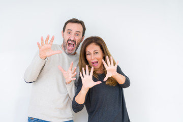 Poster - Beautiful middle age couple in love over isolated background afraid and terrified with fear expression stop gesture with hands, shouting in shock. Panic concept.