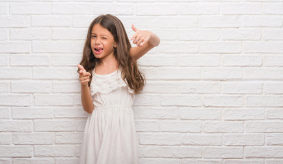 Wall Mural - Young hispanic kid over white brick wall pointing fingers to camera with happy and funny face. Good energy and vibes.