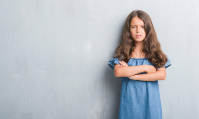 Sticker - Young hispanic kid over grunge grey wall skeptic and nervous, disapproving expression on face with crossed arms. Negative person.