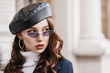 © Victoria Fox - Outdoor close up portrait of young beautiful fashionable woman with long hair wearing trendy sunglasses, hoop earrings, leather beret,  posing in street of european city. Copy, empty space for text