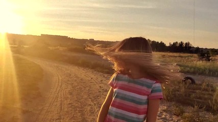 Wall Mural - Litttle girl wawing her long hair at sunset, slow motion in retro style