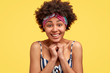 © wayhome.studio  - Headshot of pleased touched young African American woman smiles gently, feels pleased, wears striped top and headwear, isolated over yellow background. People, happiness and emotions concept