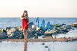 girl gymnast in red dress dancing with ribbon on the seashore