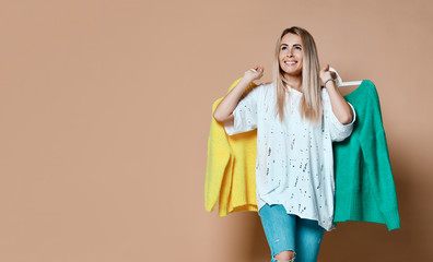 Woman shopping sale choose between two sweaters blouse green and yellow happy smiling 