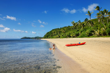 Wall Mural - Young woman with red sea kayak on a sandy beach