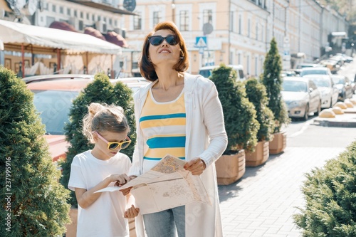 Fotografie, Tablou Mother with little daughter looking into the map of the city and traveling toget