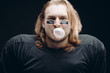 © alfa27 - Face and shoulder portrait of confident American football a prolific goal scorer with painted black stripes, looking at camera, blowing bubble from chewing gum against black background