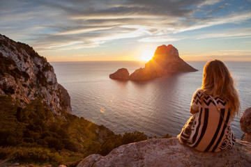 Wall Mural - Woman back to the front watching a beautiful sunset at the beach. The beach is called Es Vedra